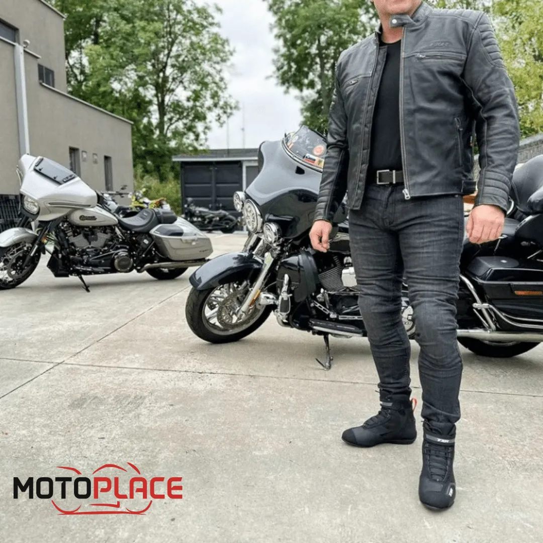 Muž v motorkářské bundě a kalhotách stojí u dvou motociklů.