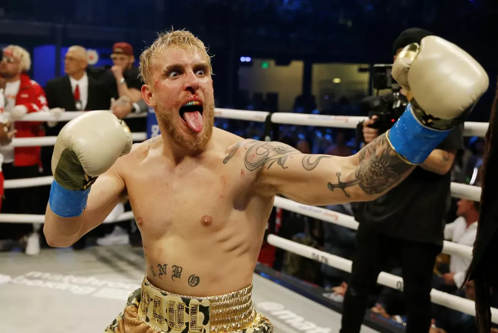 Jake Paul v boxerských rukavicích, oslavující vítězství s vyplazeným jazykem.