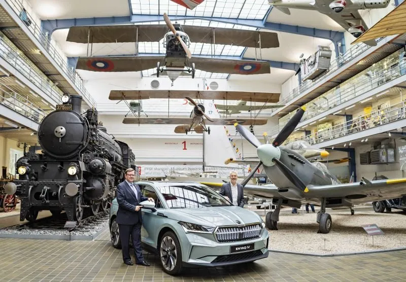 Automobil Škoda Enyaq vystavený v Národním muzeu vedle historických strojů.