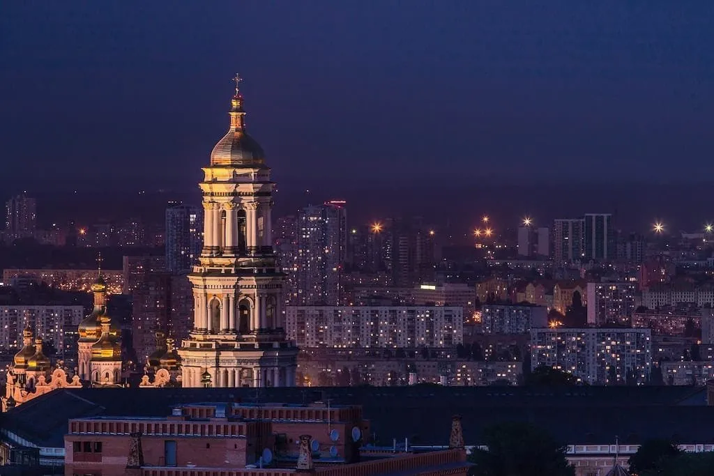 Noční panorama Kyjeva se svítilnou a městskými budovami.
