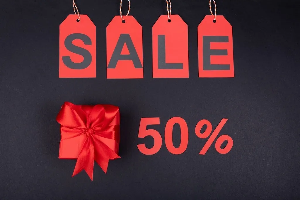 Červené cenovky se slovem SALE a dárek se 50% slevou.